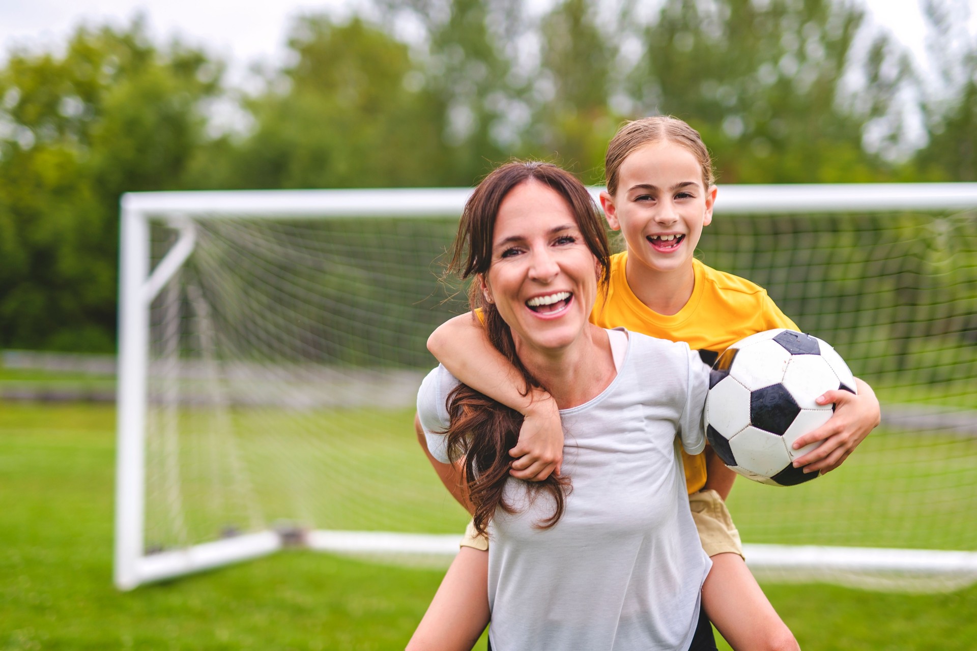 happy mother playing football outdoor on a summer day with her daughter